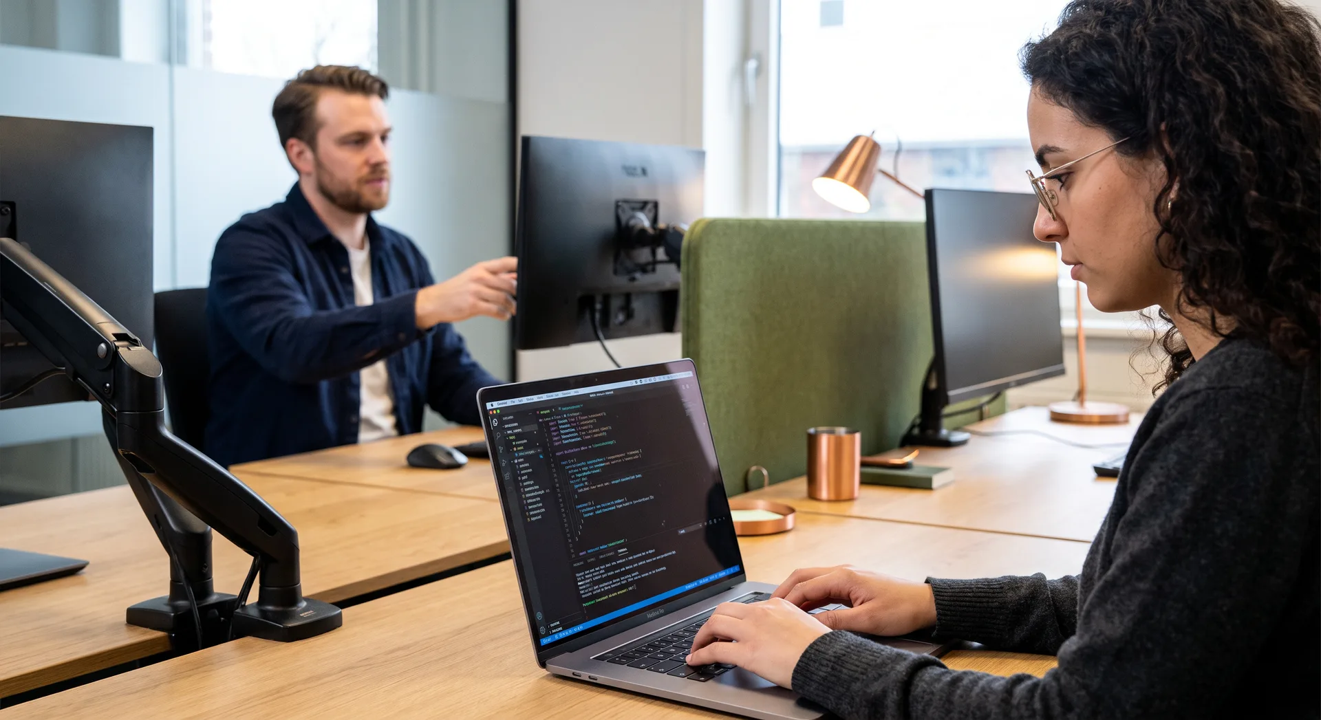 Twee developers bekijken samen een deploymentresultaat op een laptop tijdens een releasebespreking