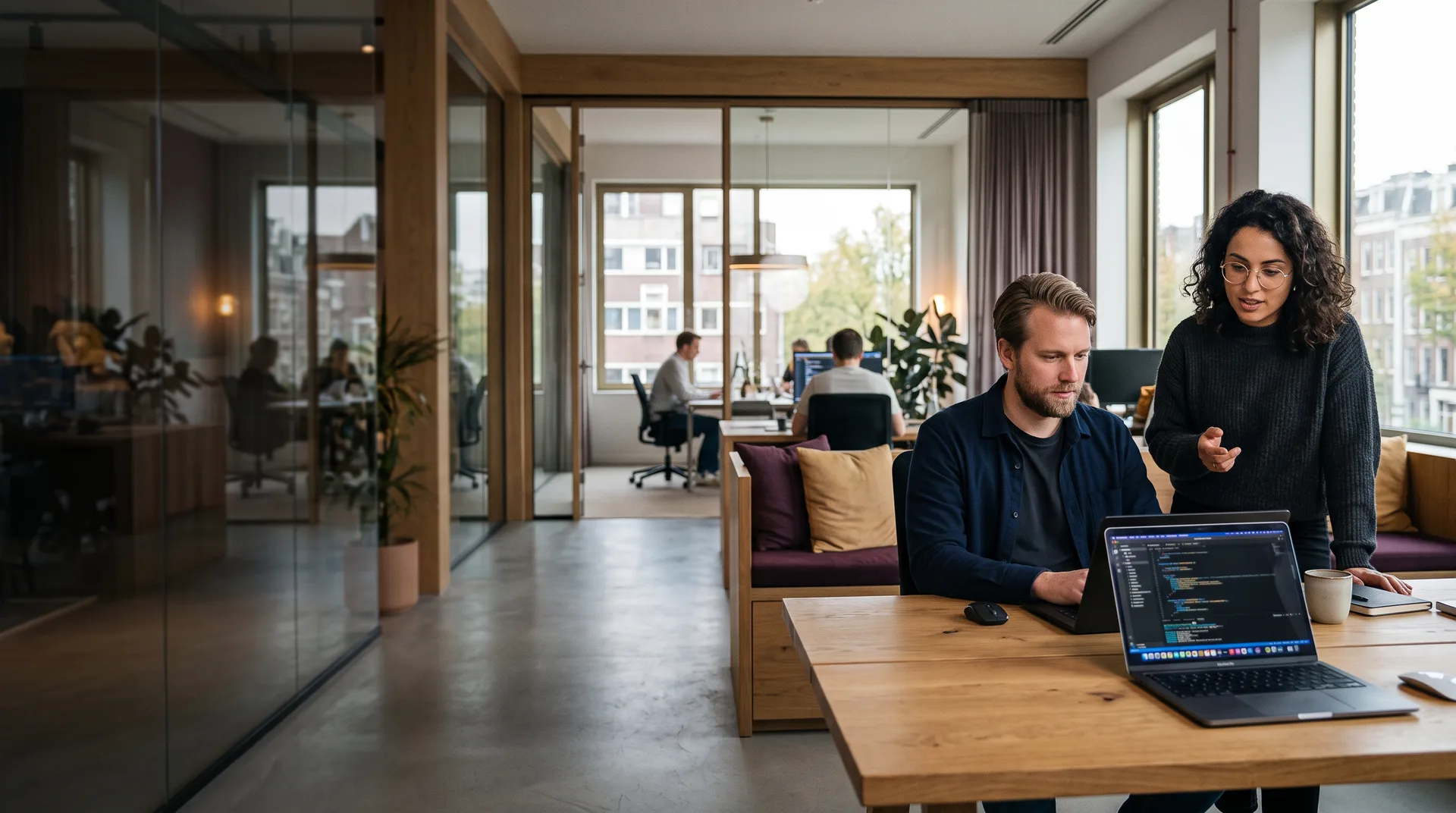 Developer werkt aan een cloudapplicatie op een laptop in de loungehoek van het Webkompanen-kantoor