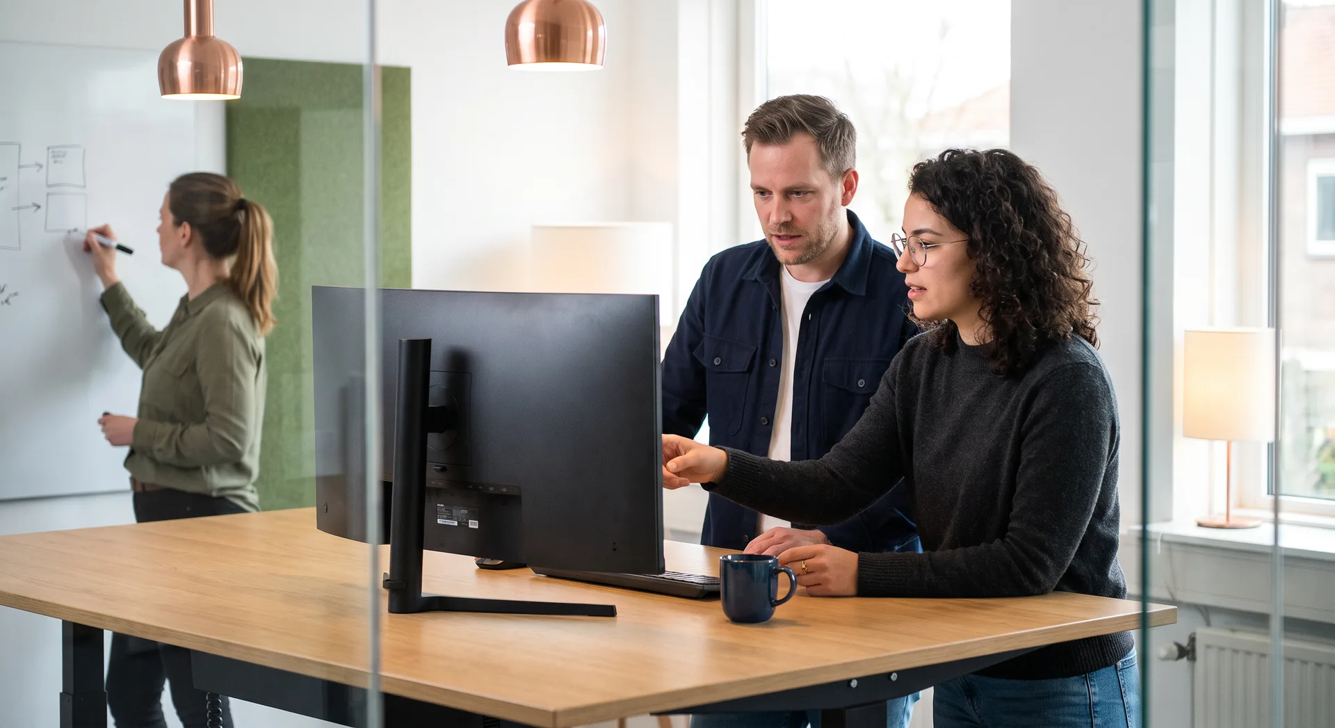 Team werkt aan een whiteboard de scope van een eerste productversie uit naast een scherm met schetsen